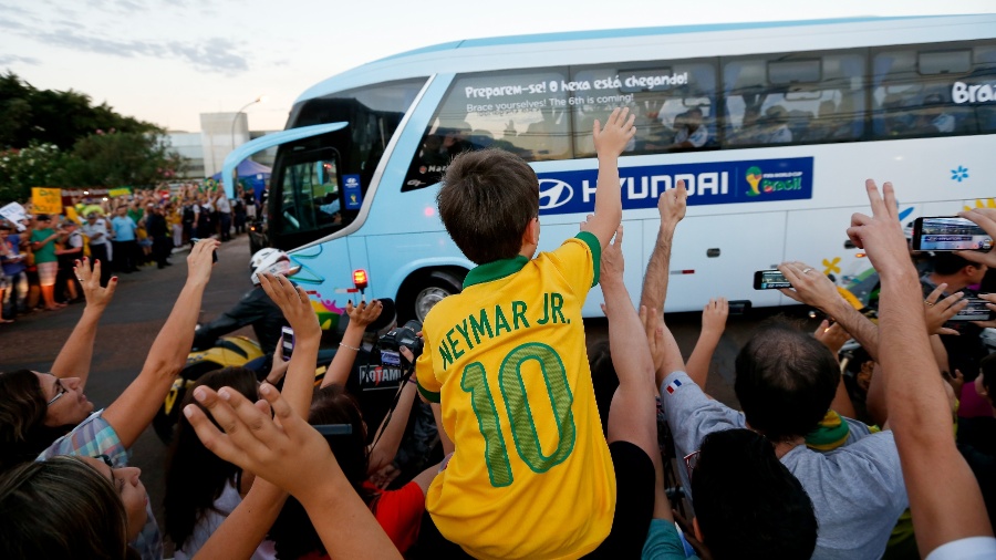 Menino com camisa de Neymar acena para ônibus da seleção brasileira durante chegada da equipe a hotel em Brasília - Pedro Ladeira/Folhapress