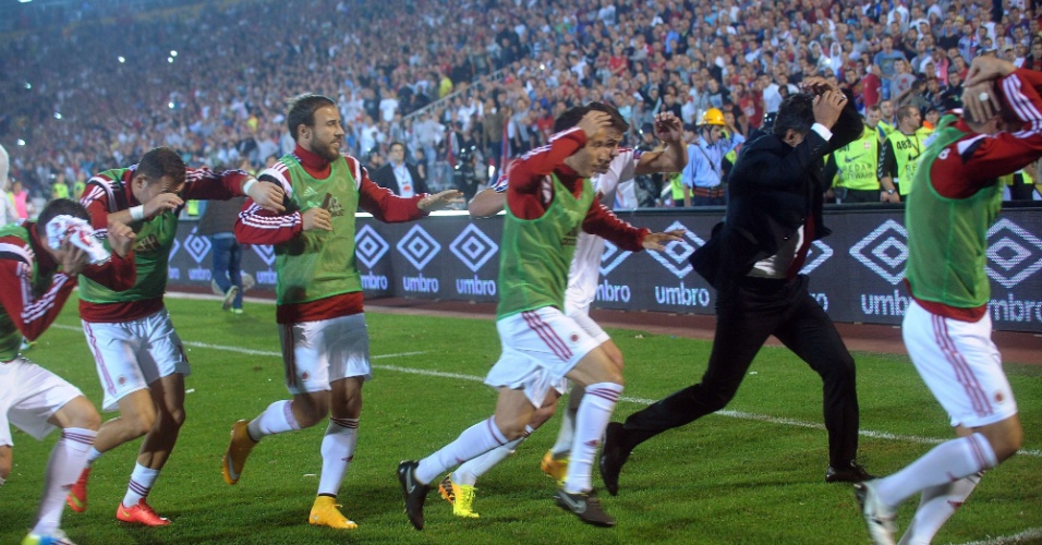 Jogadores da Albânia correm para tentar se proteger da confusão causada por um drone em um jogo das Eliminatórias da Euro