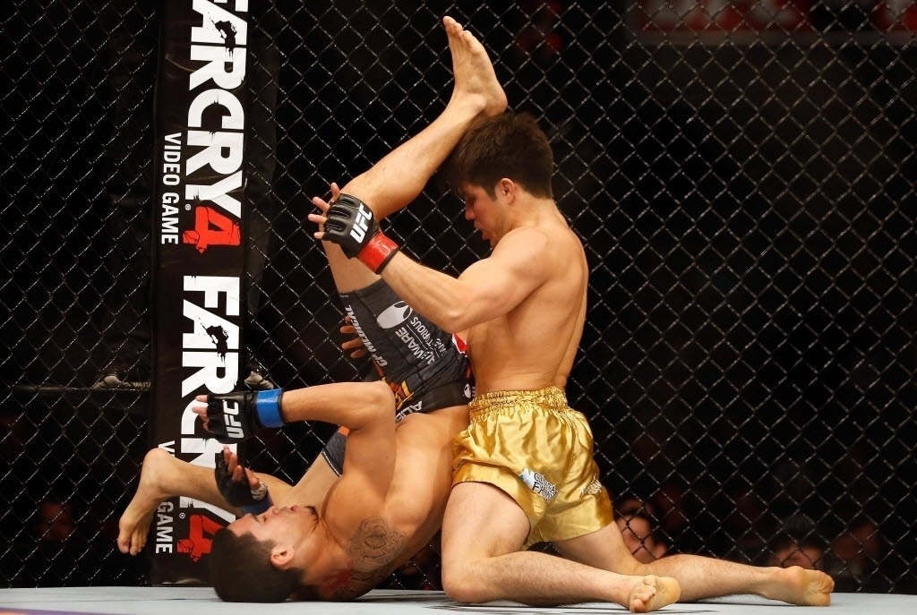 13.dez.2014 - Henry Cejudo (dir.) domina o combate contra Dustin Kimura; Cejudo, que é campeão olímpico de wrestling, venceu a luta, em sua estreia no UFC, e se manteve invicto no MMA, com sete vitórias - Christian Petersen/Getty Images/AFP