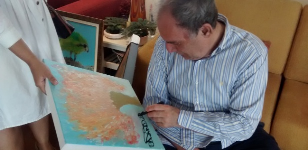 Osmar Santos assina um de seus quadros, que deu de presente à esposa de seu filho - Adriano Wilkson/UOL - Adriano Wilkson/UOL