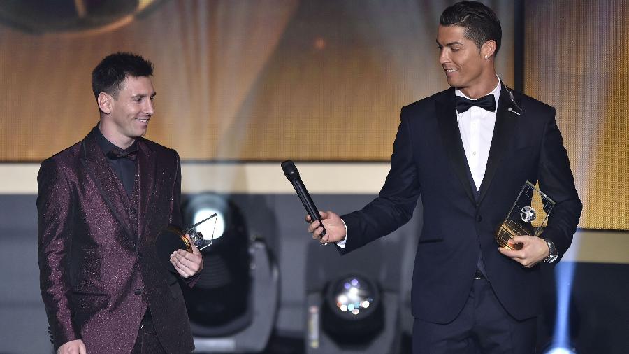 Cristiano Ronaldo passa o microfone para Lionel Messi durante o evento da Bola de Ouro da Fifa. Os dois estão na seleção da Fifa, em 2015 - AFP PHOTO / FABRICE COFFRINI