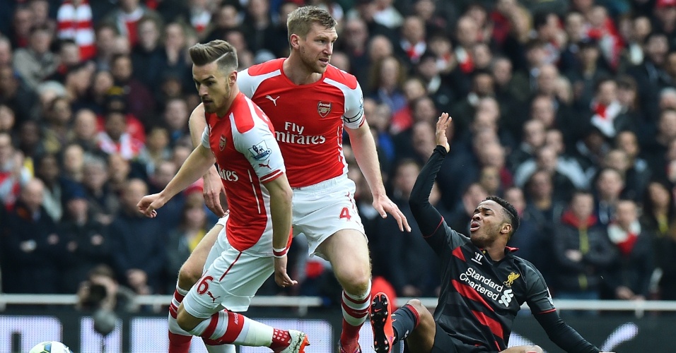 Raheem Sterling, do Liverpool, não gosta de falta cometida por Per Mertesacker, no clássico entre Arsenal e Liverpool, pelo Campeonato Inglês