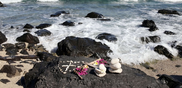 Flores e seixos foram deixados à beira do mar na praia em que Elio Canestri morreu - RICHARD BOUHET/AFP