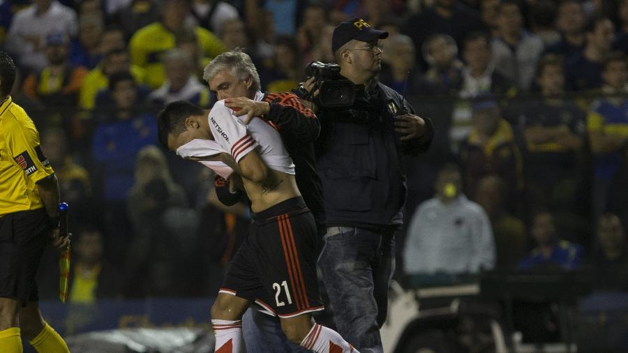 Leonel Vangioni, do River, cobre o rosto após ser atingido por gás no confronto entre Boca e River na Libertadores - EFE/Iván Fernández