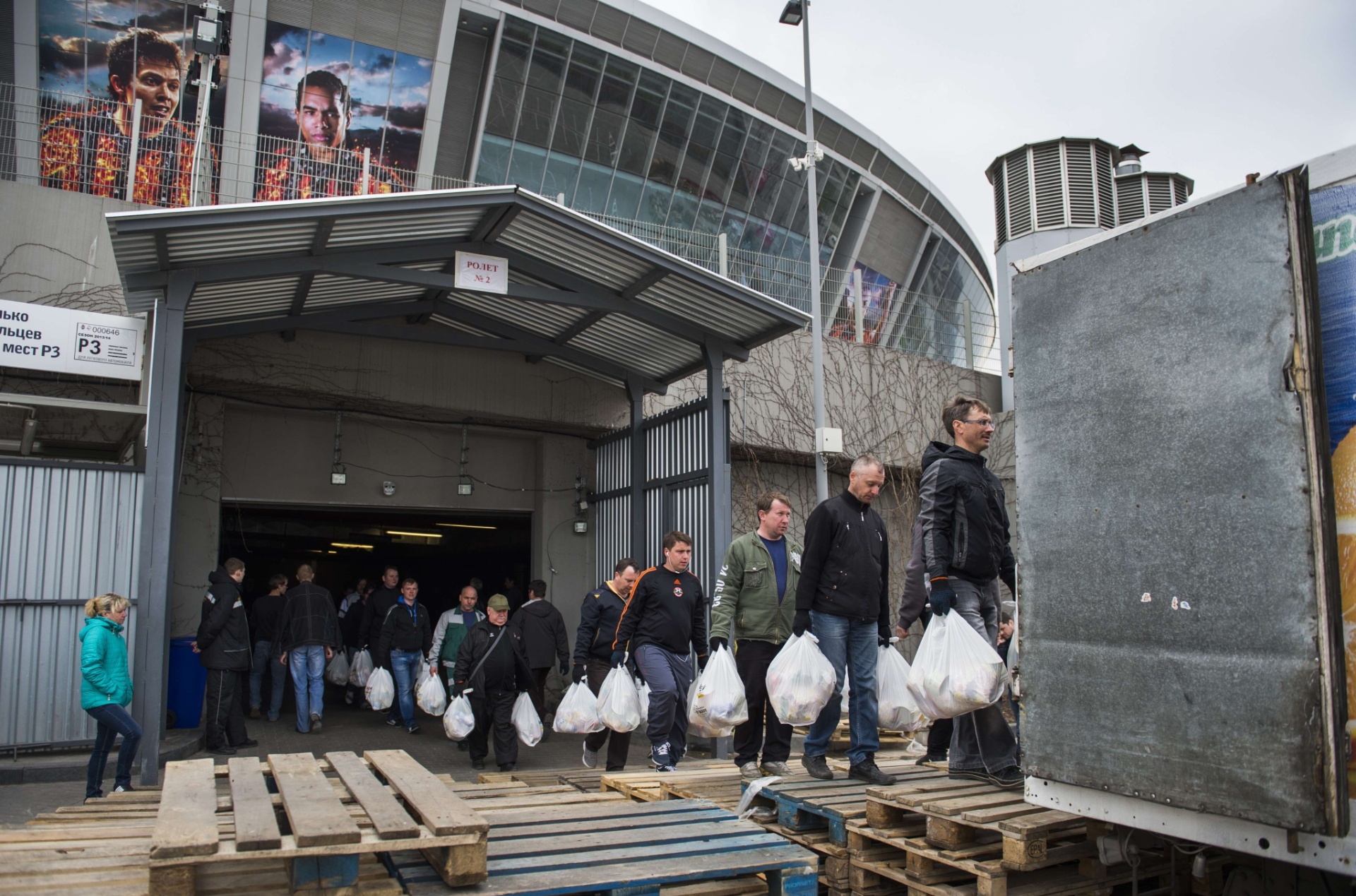Pôsteres de Bernard e Alex Teixeira pendurados no estádio enquanto voluntários levam comidas para os caminhões - undefined