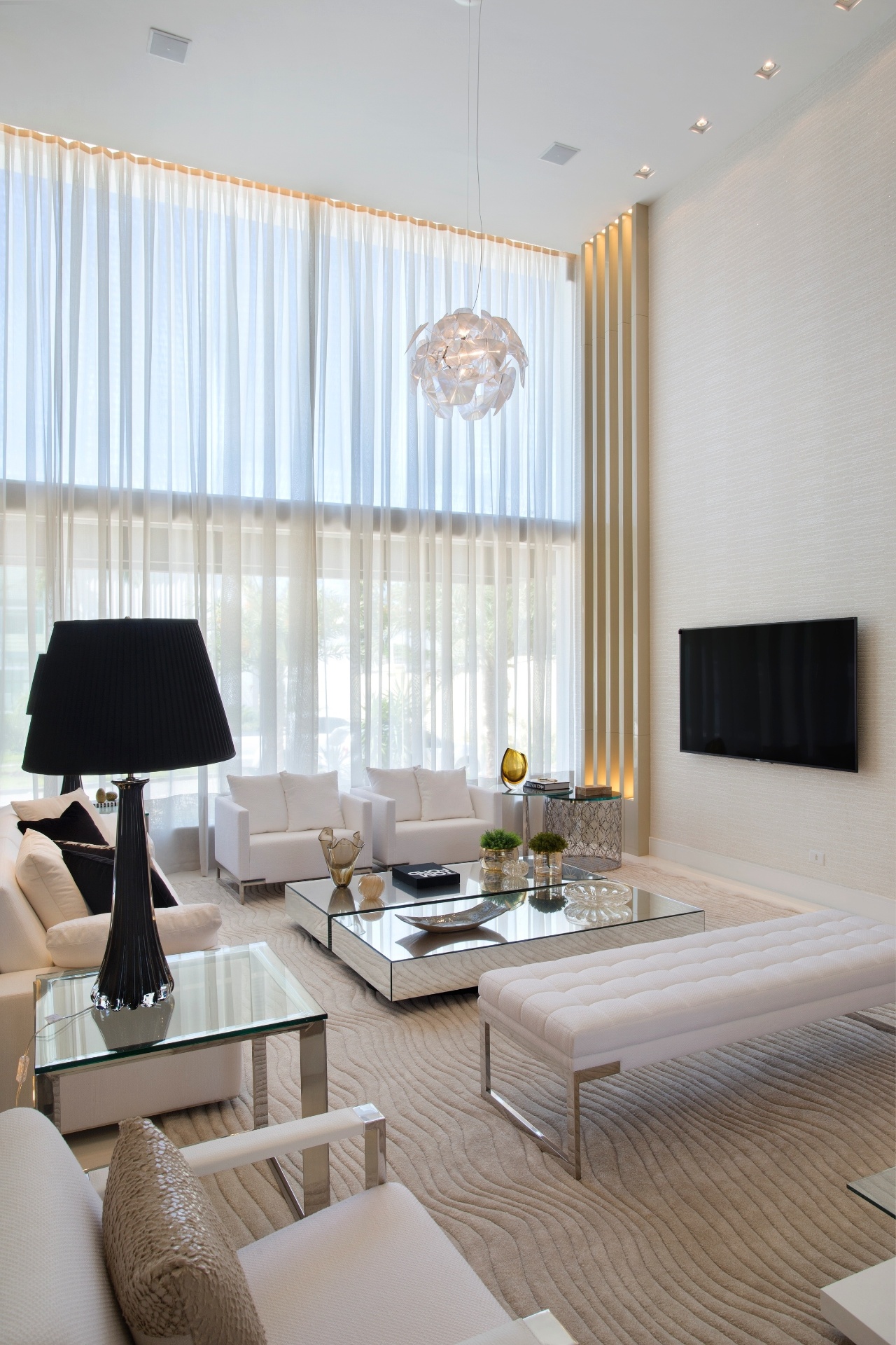 Sala de estar da casa de Alex Teixeira tem pé direito duplo, predominância por linhas retas e cores claras. Itens de decoração na cor preta como o abajour dão elegância ao ambiente - Divulgação