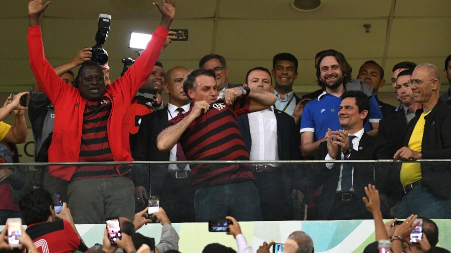 Jair Bolsonaro, ladeado por Hélio Lopes (PSL-RJ) e Sérgio Moro, no estádio Mané Garrincha para a partida CSA x Flamengo - Edu Andrade/FatoPress/Estadão Conteúdo