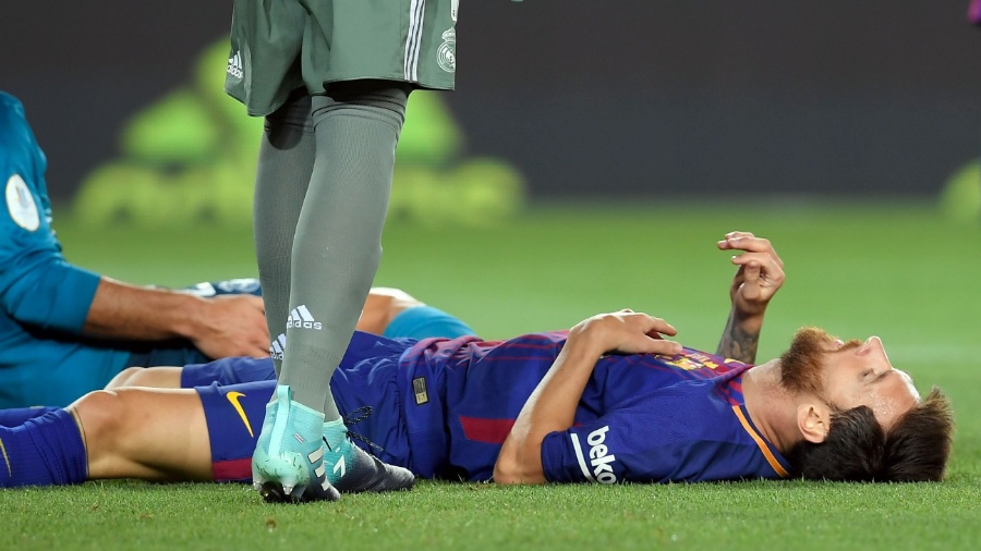 Messi caído no gramado durante jogo do Barcelona contra o Real Madrid - LLUIS GENE /AFP