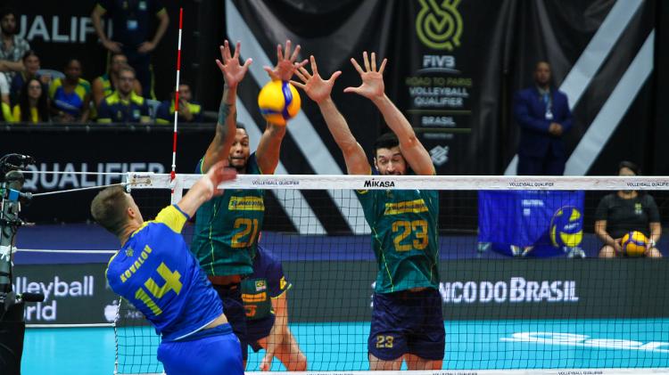 Jogadores da seleção brasileira tentam bloquear ataque da Ucrânia no Pré-Olímpico de vôlei masculino