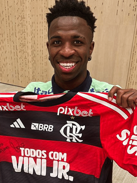 Vini Jr. segurando a camisa antirracista usada pelo Flamengo