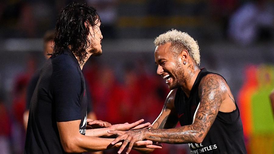 Neymar sorri e cumprimenta Cavani durante treino do PSG - FRANCK FIFE / AFP