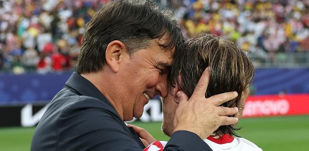 A determined Croatian football player in a red and white checkered jersey, looking focused on the pitch during a World Cup match.
