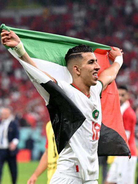 O zagueiro Jawad El Yamiq, do Marrocos, com a bandeira da Palestina após vitória sobre a Espanha na Copa do Mundo - NATALIA KOLESNIKOVA / AFP