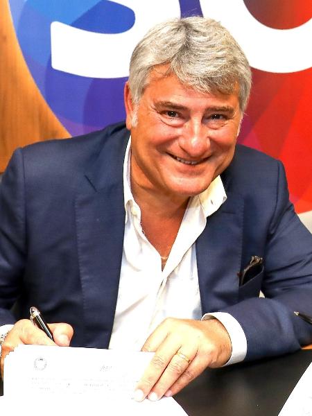 Cleber Machado sorri ao assinar contrato com o SBT