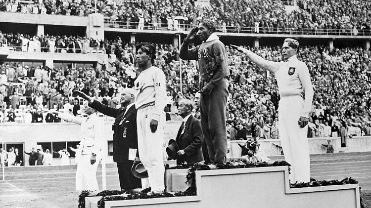 Pódio do salto em distância em 1936 tem Jesse Owens no lugar mais alto. O norte-americano levou quatro ouros nos jogos realizados na Alemanha nazista