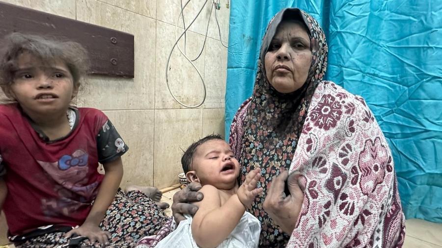 Mulher palestina com seus dois filhos após ataque de Israel em Gaza