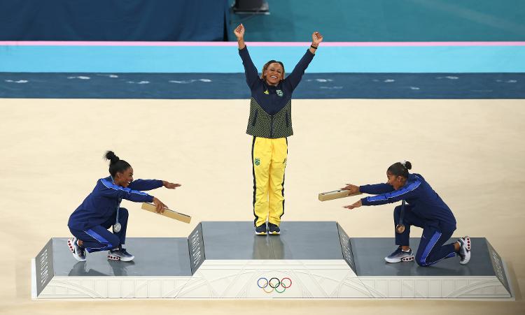 Rebeca Andrade recebe reverência de Simone Biles e Jordan Chiles no pódio do solo em Paris 2024. Rebeca levou o ouro olímpico