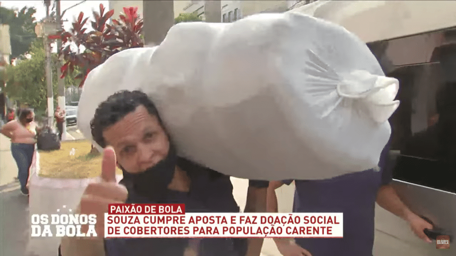 Souza carrega pacote com cobertores para entregar a projeto social do Padre Júlio Lancelotti - Reprodução/TV Band