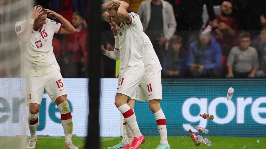 Jogadores da Polônia se protegem de garrafas atiradas pela torcida da Albânia - REUTERS/Florion Goga