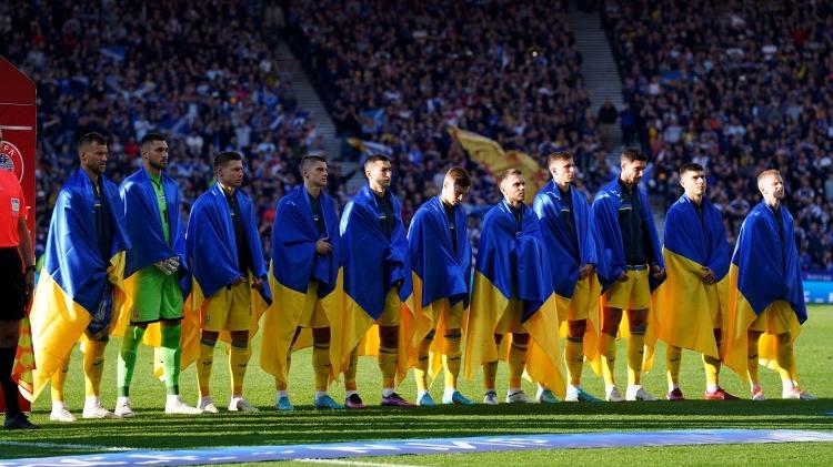 Jogadores da Ucrânia entram em campo enrolados com a bandeira do país - Andrew Milligan/PA Images via Getty Images - Andrew Milligan/PA Images via Getty Images