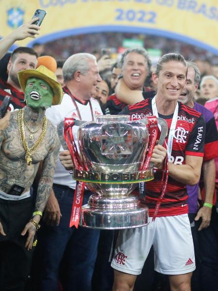 Filipe Luis, do Flamengo, posa com a taça da Copa do Brasil; ao lado, um homem de "O Máscara" - Gilvan de Souza / Flamengo