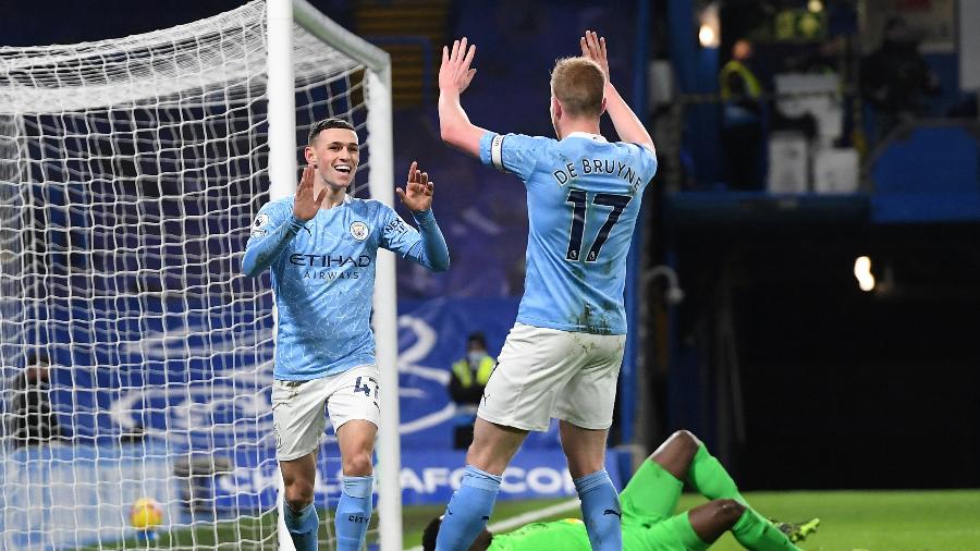 Phil Foden e De Bruyne comemoram segundo gol do Manchester City sobre o Chelsea, no Stamford Bridge - Andy Rain/AFP