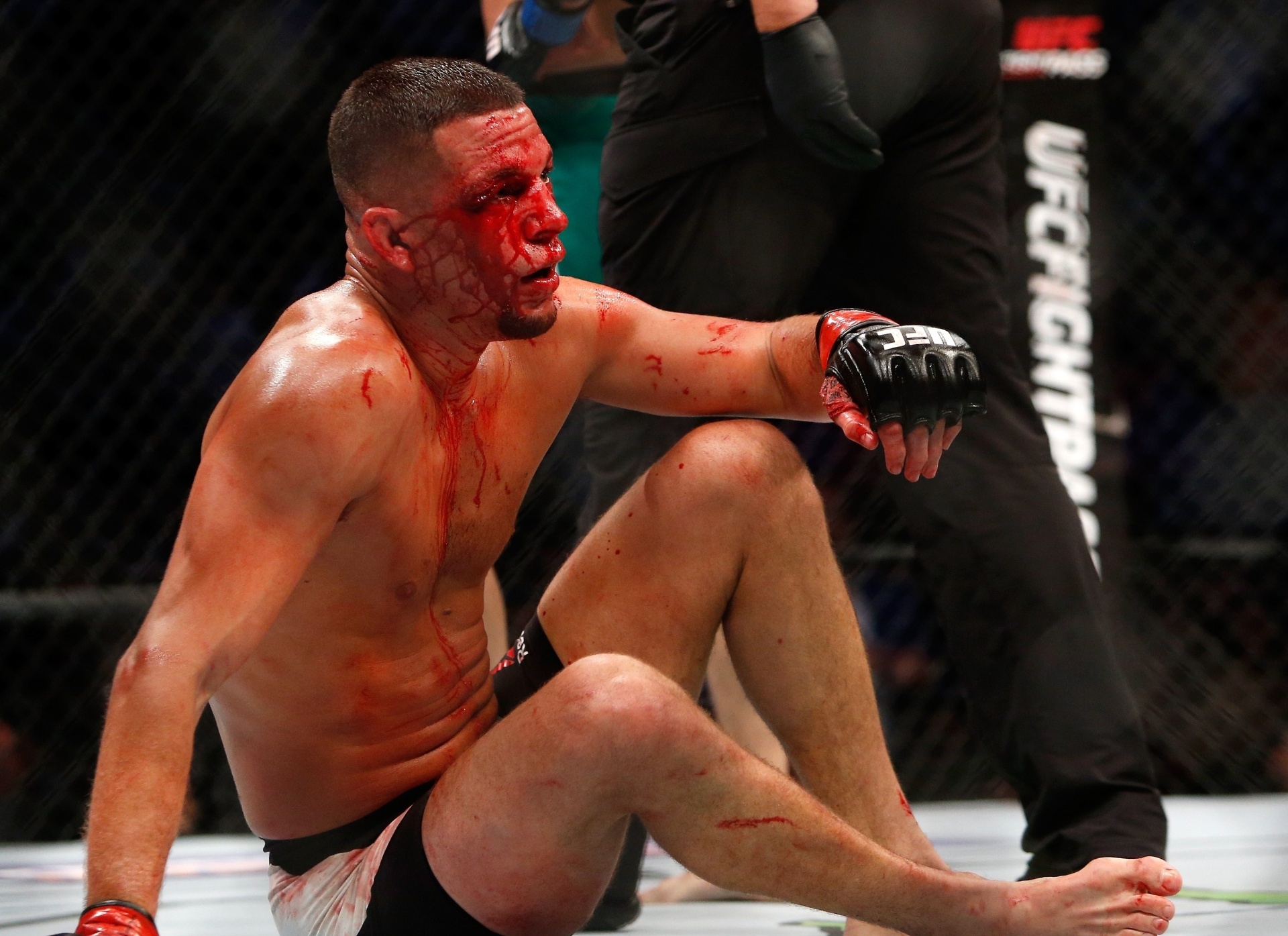 Com o rosto ensanguentado, Nate Diaz tenta se levantar durante a luta contra Conor McGregor - Steve Marcus/Getty Images