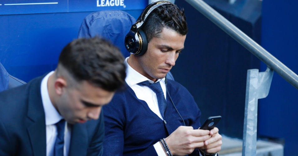 Cristiano Ronaldo usa o celular no banco de reservas que será destinado ao Real Madrid contra o Manchester City
