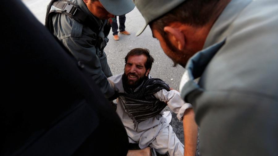 Funcionários da polícia afegã ajudam civil após atentado terrorista em Kabul - Mohammad Ismail/Reuters