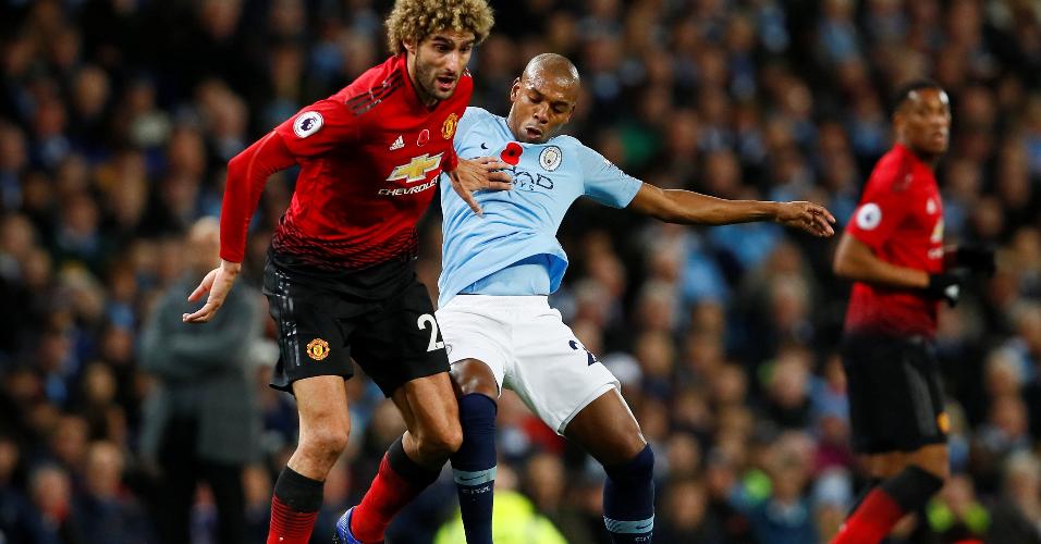 Fernandinho tenta dar o bote em Marouane Fellaini no jogo entre Manchester City e Manchester United pelo Campeonato Inglês