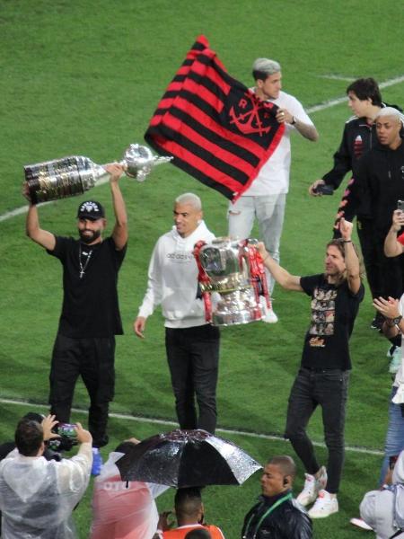 Jogadores do Flamengo levam taças da Copa do Brasil e da Libertadores ao campo - Foto: Luiza Sá/UOL