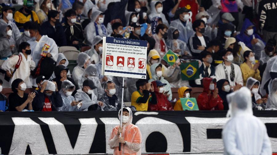 Homem exibe cartaz em português com regras durante amistoso entre Brasil e Japão - REUTERS/Issei Kato