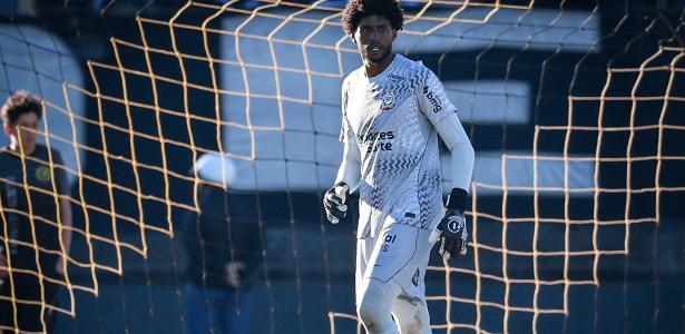 Ein einzelner Fußballspieler steht auf einem regennassen Spielfeld und blickt deprimiert unter dramatischer Stadionbeleuchtung drein.