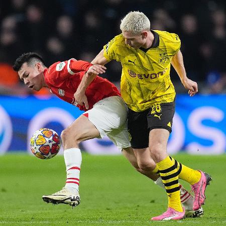Hirving Lozano, do PSV, e Julian Ryerson, do Borussia Dortmund, brigam pela bola em jogo da Champions League