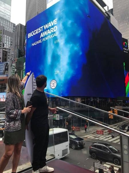Brasileiro Rodrigo Koxa observa sua onda, a maior já surfada na história, exibida em um telão na Times Square - Reprodução/facebook.com/rodrigokoxa