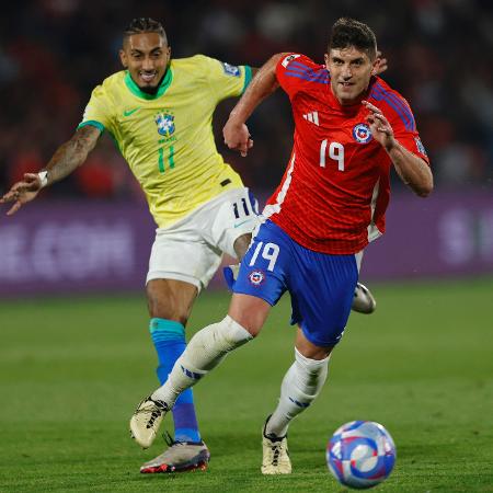Raphinha e Kuscevic em ação durante jogo entre Brasil e Chile pelas Eliminatórias - JAVIER TORRES/AFP