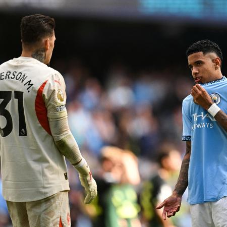 Savinho conversa com o goleiro Ederson em partida do Manchester City