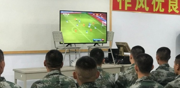 Jogadores chineses acompanham partida da seleção local durante período de treinos militares - Reprodução/CCTV