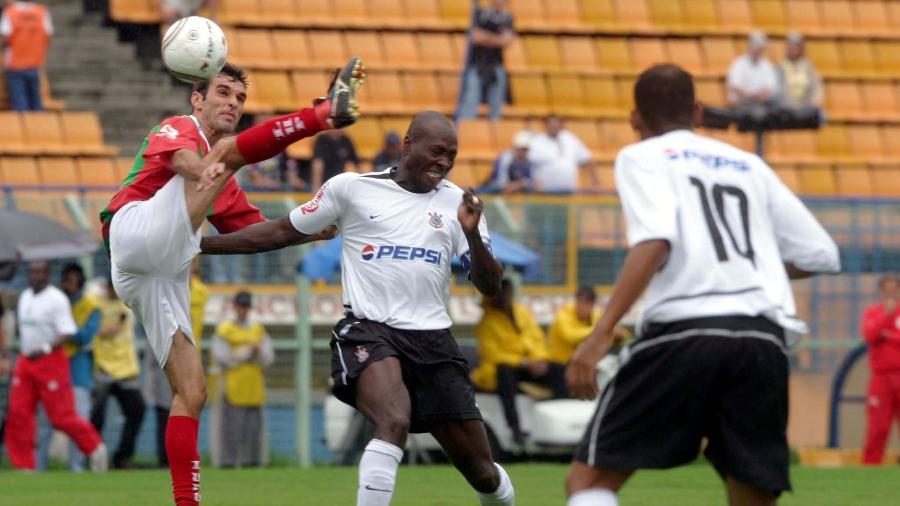 Rincón, observado por Gil, disputa a bola durante duelo Corinthians e Portuguesa Santista no Pacaembu, em 2004 - Keiny Andrade/Folha Imagem