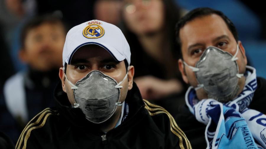 Após a Espanha confirmar os primeiros casos de coronavírus nesta semana, torcedores usam máscaras de proteção em partida entre Real Madrid e Manchester City, pela ida das oitavas de final da Liga dos Campeões, em Madri  - Susana Vera/Reuters