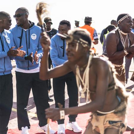 Atletas de Botsuana acompanham apresentação de dança em sua chegada ao país