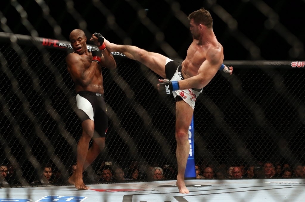 Anderson Silva tenta se defender de chute alto de Michael Bisping, na luta principal do UFC em Londres, neste sábado (27)