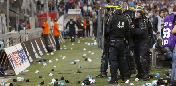 Policiais se protegem enquanto torcedores arremessam objetos ao gramado - Philippe Laurenson/Reuters