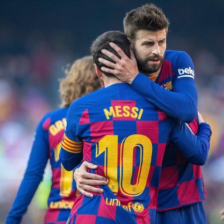 Gerard Piqué abraça Lionel Messi durante jogo do Barcelona em fevereiro de 2020