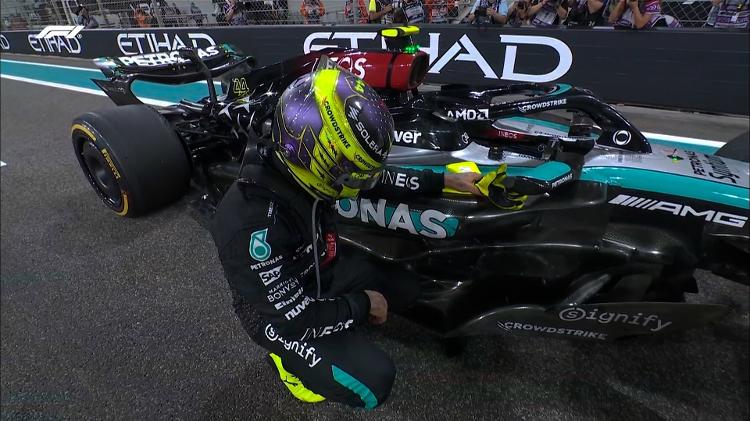 Lewis Hamilton se ajoelha ao lado do carro após sua última corrida pela Mercedes