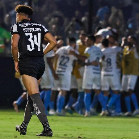Adryelson, do Botafogo, se lamenta enquanto jogadores do Grêmio comemoram