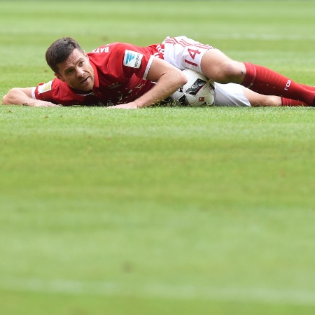 Xabi Alonso, volante do Bayern, fica deitado no chão durante o jogo contra o Colônia, pelo Camp. Alemão -  AFP PHOTO / CHRISTOF STACHE