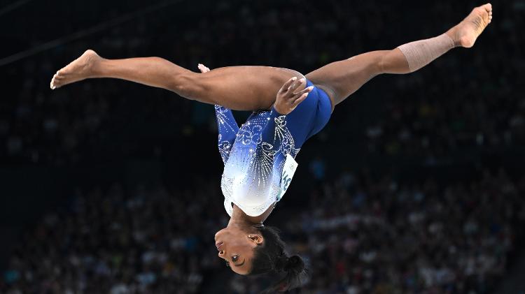 Simone Biles com as pernas paralelas à trave de equilíbrio