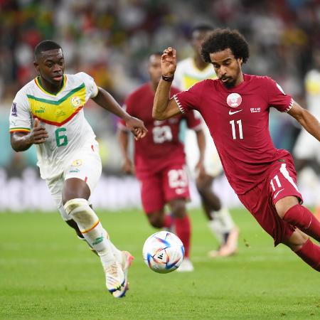 Akram Afif divide bola com Nampalys Mendy na partida entre Qatar x Senegal - Mike Hewitt - FIFA/FIFA via Getty Images