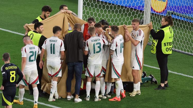 Jogadores e médicos fazem tenda para atendimento de Barnabas Varga, da Hungria, após choque de cabeça durante jogo contra a Escócia, pela Eurocopa